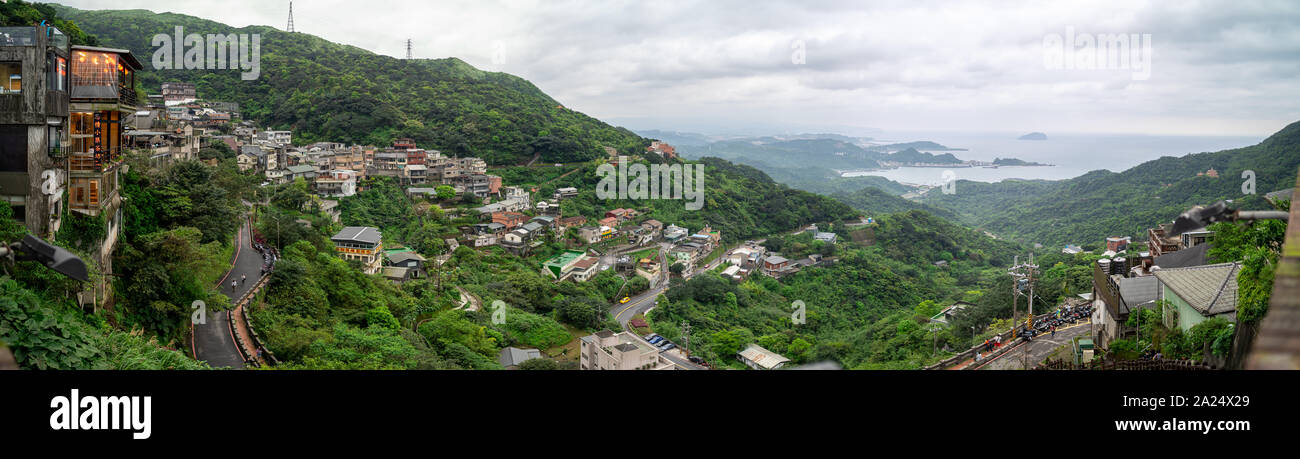 Taipei, Taiwan: Wide Panorama of green hills, tea houses and villages in Jiufen with the ocean in the distance on cloudy day Stock Photo