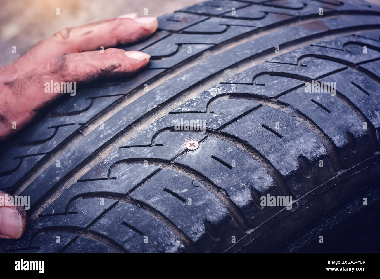 Hands on flat car tire punctured with a screw closeup - Stock Photo