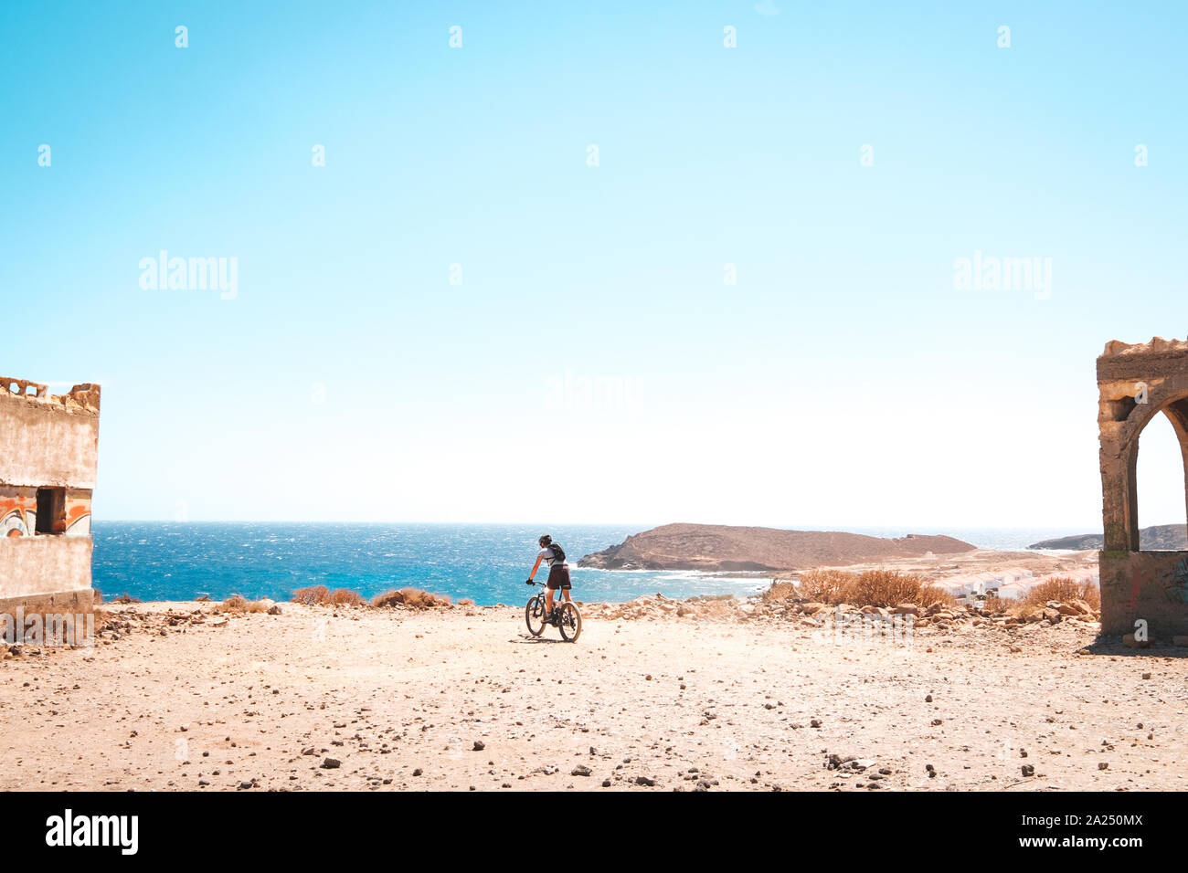 person on mountain bike bicycle in desert landscape near coast with ocean background Stock Photo