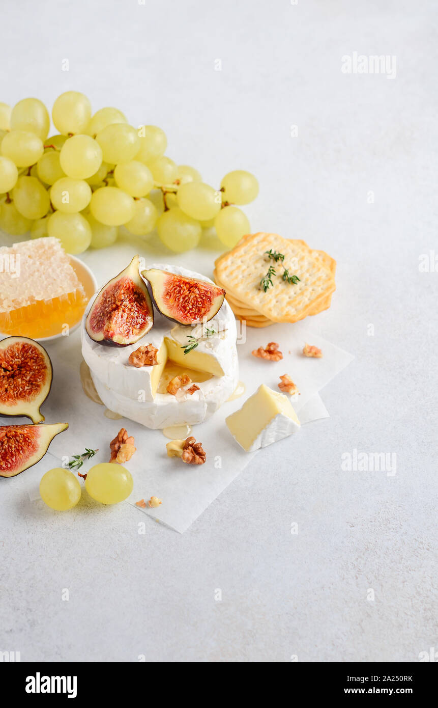 Brie or camembert cheese with figs, grapes, honey and nuts. Stock Photo
