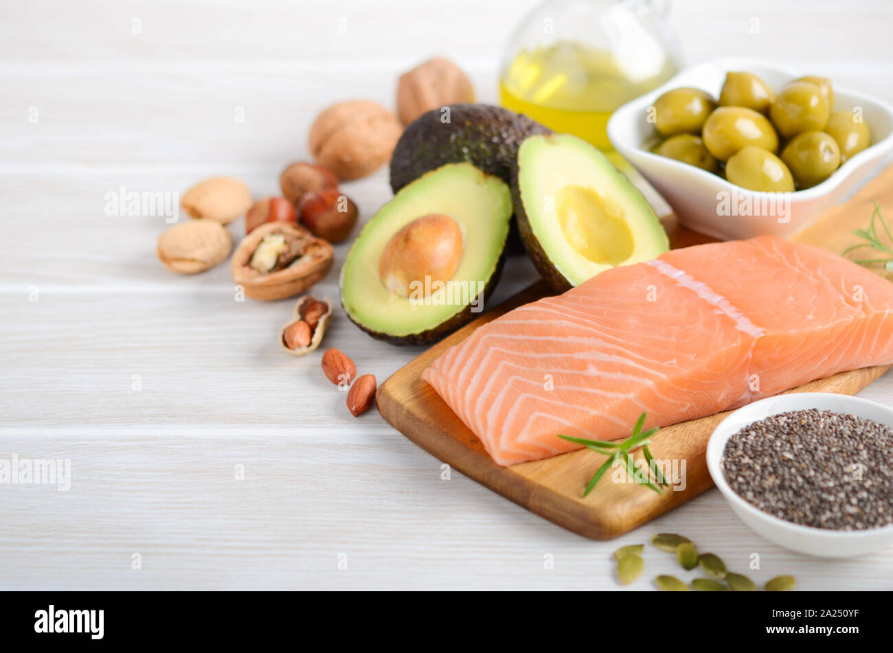 Selection of healthy unsaturated fats, omega 3 - fish, avocado, olives, nuts and seeds. Stock Photo