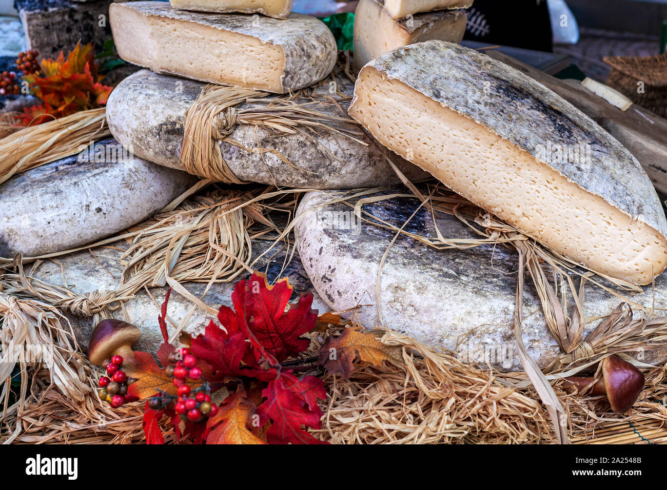 Close-up view of semi-hard cheese wrapped in straw on the stall at the market in Italy. Stock Photo