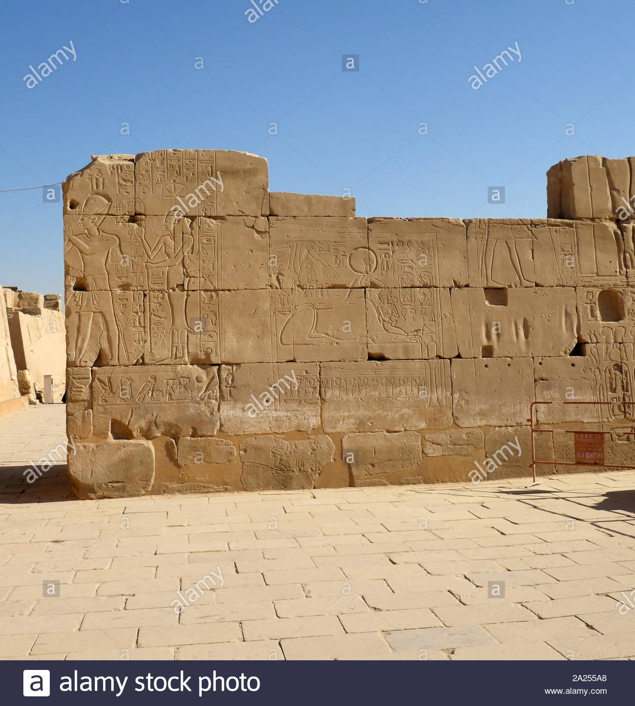 Relief depicting a king and queen and the Ram headed god Khnum at Karnak Temple Complex, in Luxor, Egypt. Construction at the complex began during the reign of Senusret I in the Middle Kingdom and continued into the Ptolemaic period, although most of the extant buildings date from the New Kingdom. The area around Karnak was the main place of worship of the eighteenth dynasty Theban Triad with the god Amun as its head. It is part of the monumental city of Thebes. Stock Photo