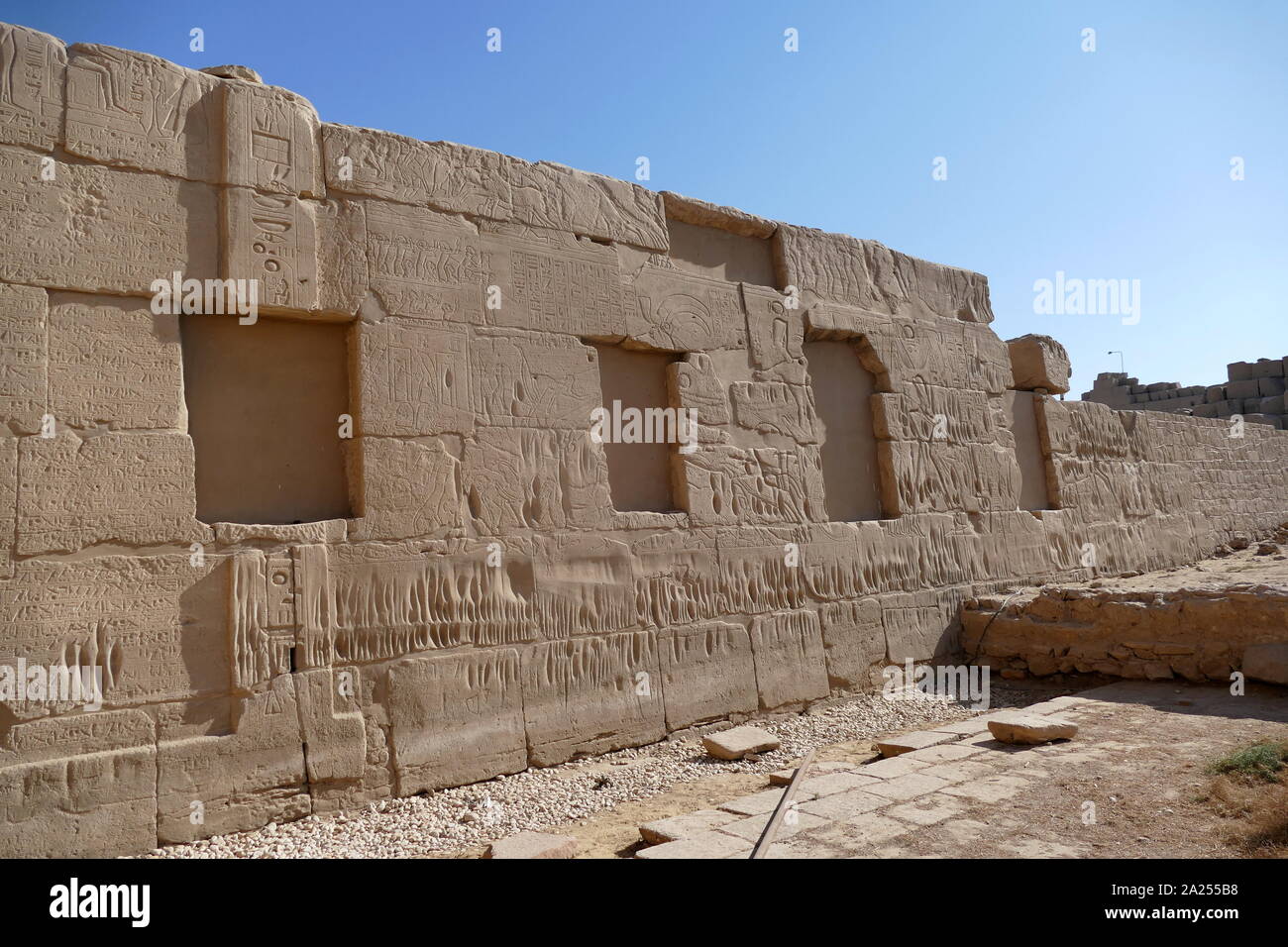 Carved relief at Karnak Temple Complex, in Luxor, Egypt. Construction at the complex began during the reign of Senusret I in the Middle Kingdom and continued into the Ptolemaic period, although most of the extant buildings date from the New Kingdom. The area around Karnak was the main place of worship of the eighteenth dynasty Theban Triad with the god Amun as its head. It is part of the monumental city of Thebes. Stock Photo