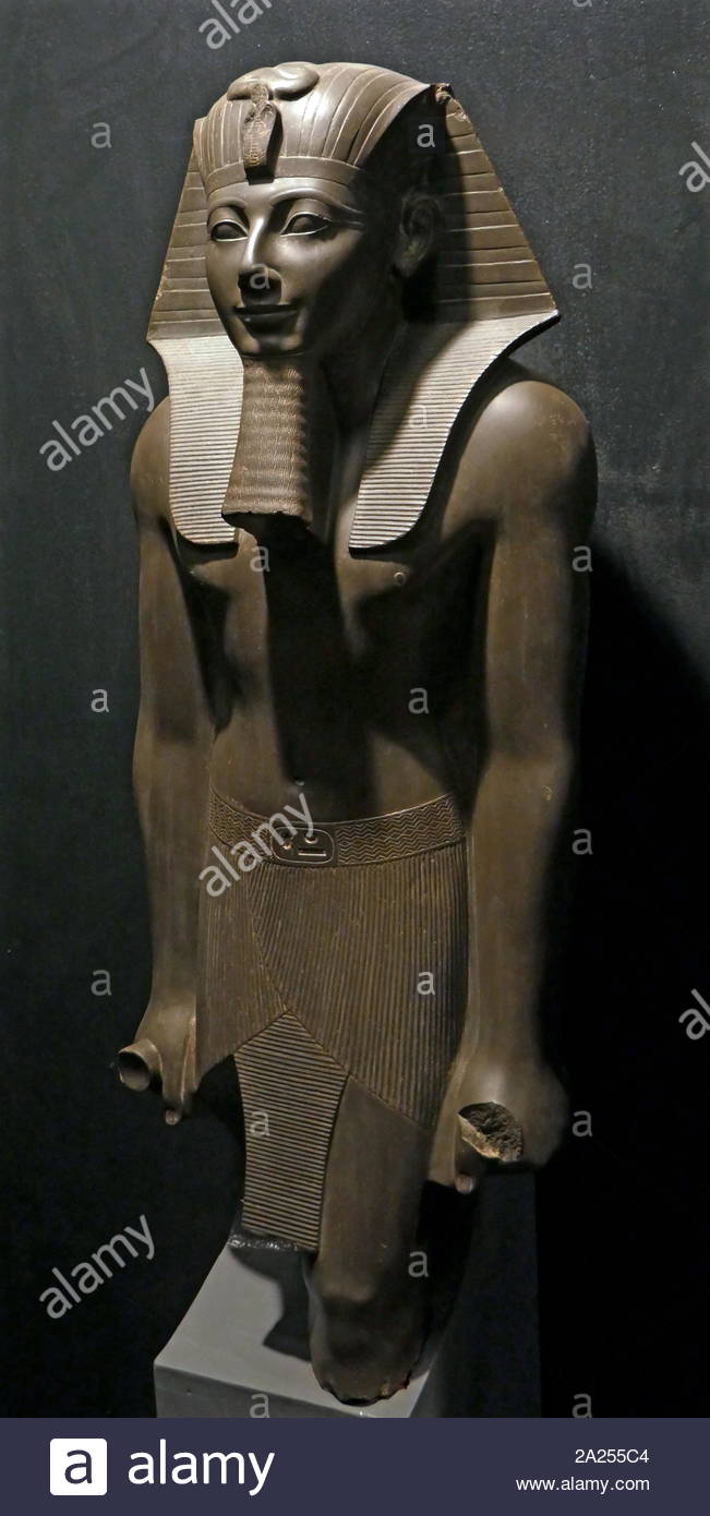 Statue Of King Tutmosis III. Greywacke, New Kingdom, 1490 -1436 B.C. Karnak Temple. He is shown wearing the nemes headdress with the protective uraeus, false beard and an ornate kilt with a buckle inscribed with his cartouche. Stock Photo