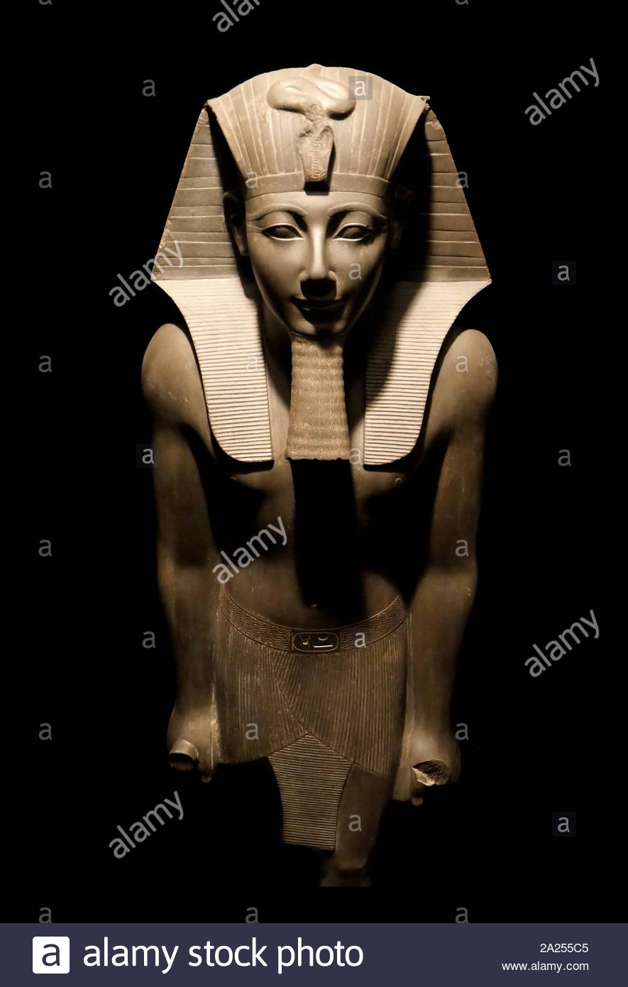 Statue Of King Tutmosis III. Greywacke, New Kingdom, 1490 -1436 B.C. Karnak Temple. He is shown wearing the nemes headdress with the protective uraeus, false beard and an ornate kilt with a buckle inscribed with his cartouche. Stock Photo