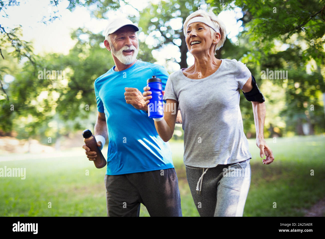 Beautiful senior couple running outside in forest Stock Photo