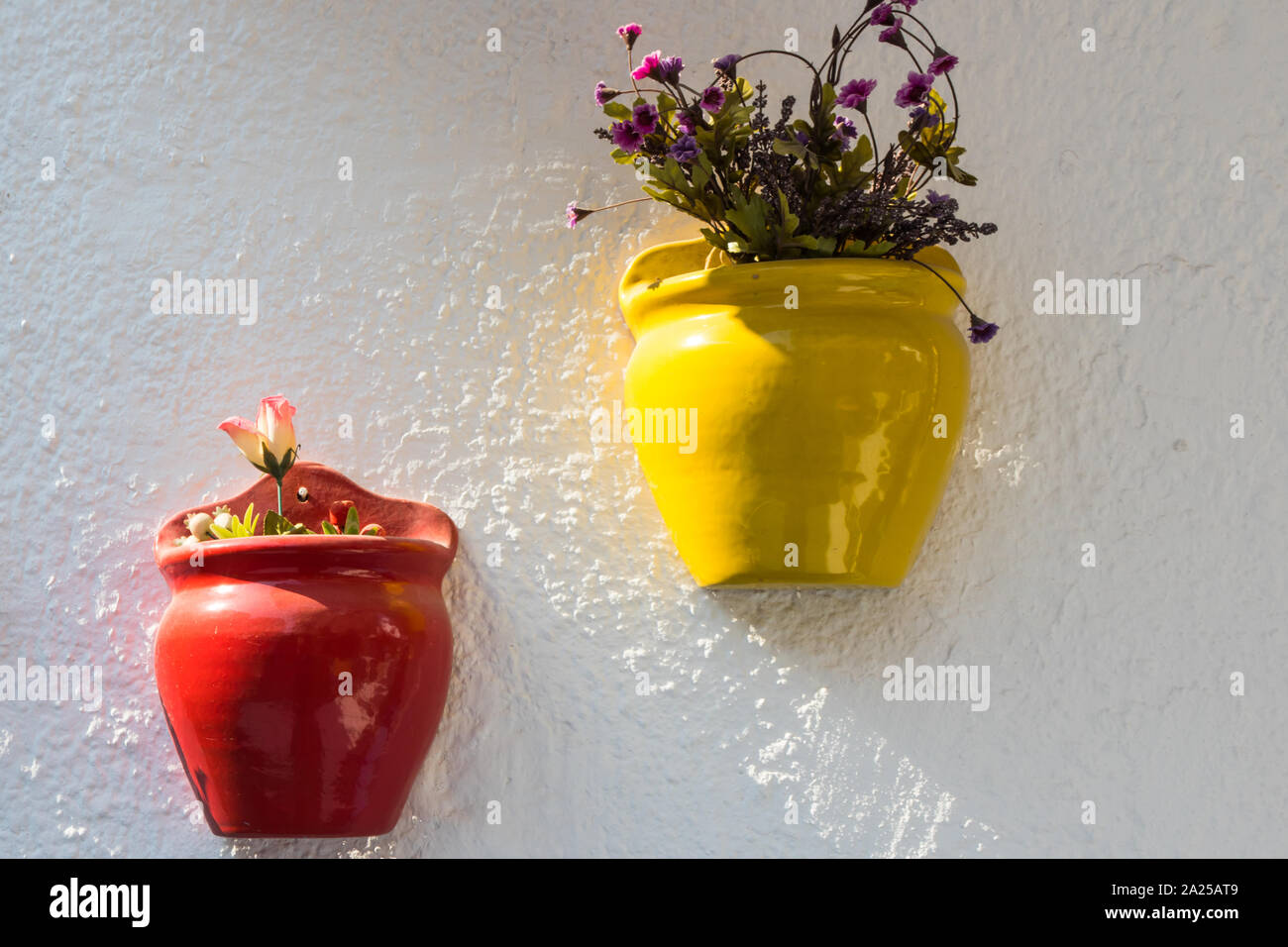 Colourful plant pots with plants hanging against a white wall in Alacati, Izmir, Turkey Stock Photo