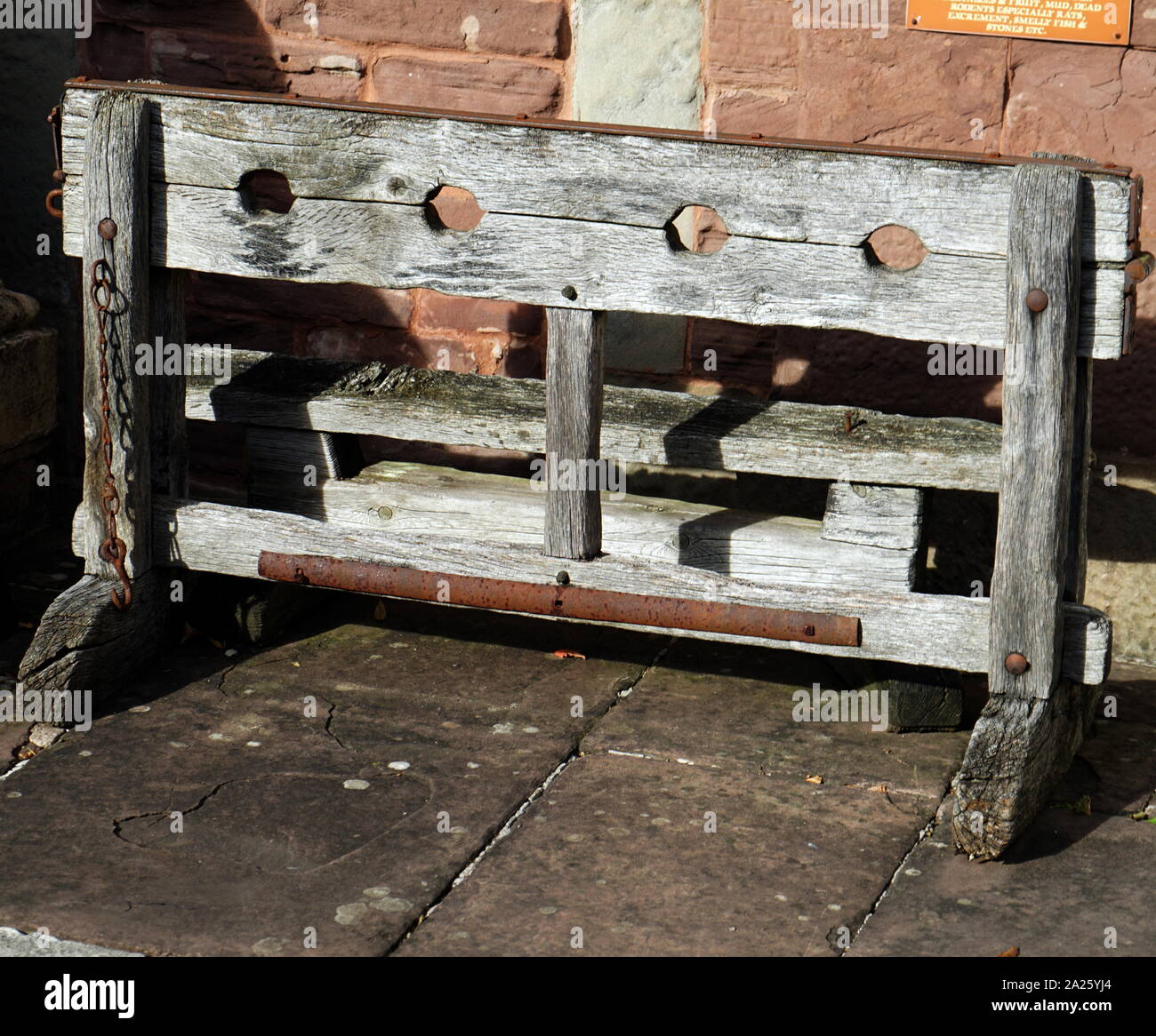 A replica of medieval wooden stocks. Stocks were restraining devices used as a formal of corporal punishment and public humiliation. Stock Photo