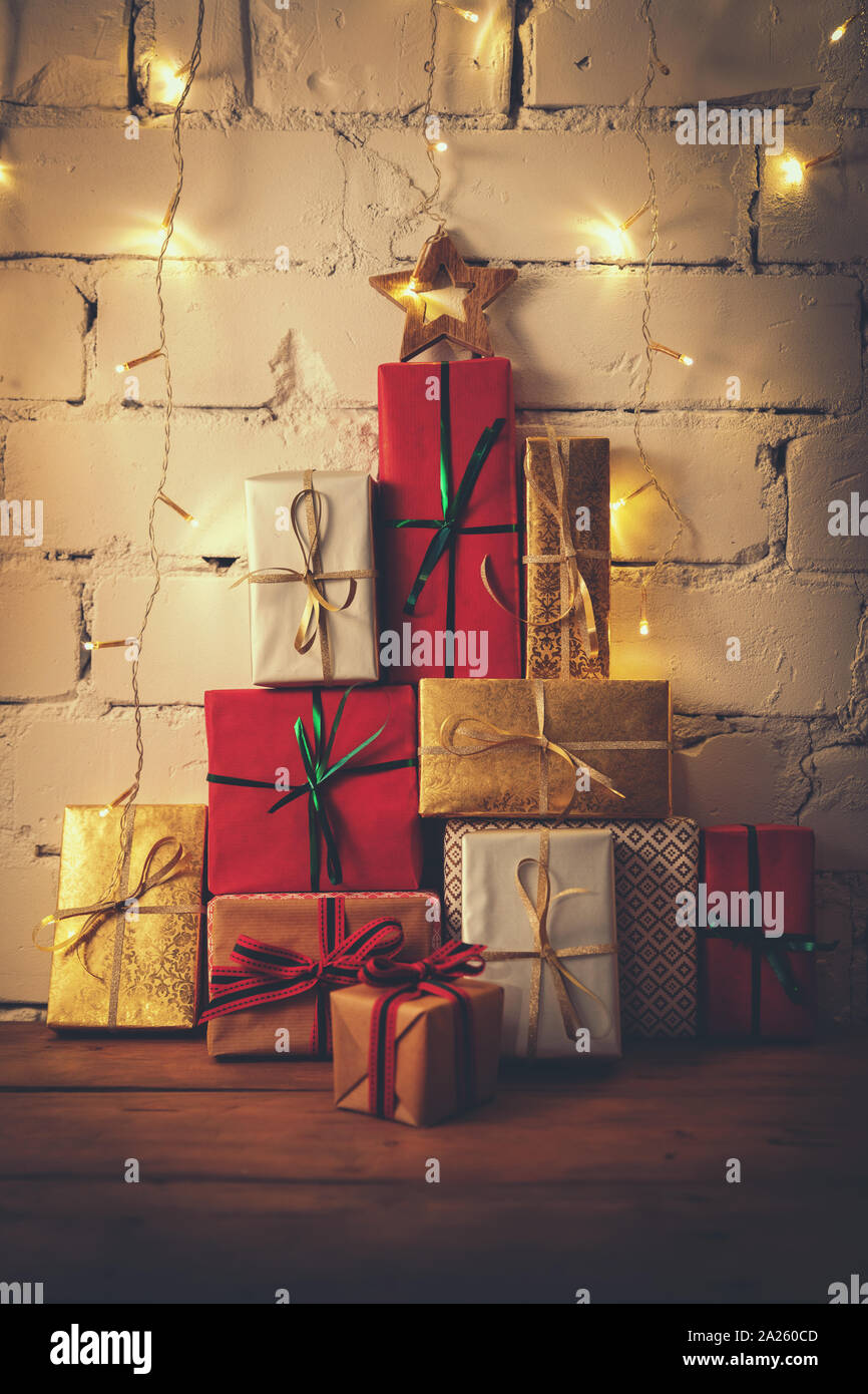 stack of christmas gifts on white brick wall background Stock Photo