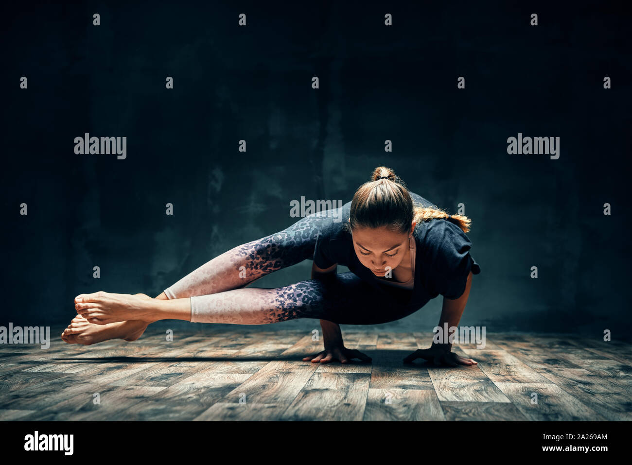 Woman doing yoga Astavakrasana/Eight Angle Pose.Toned image Stock