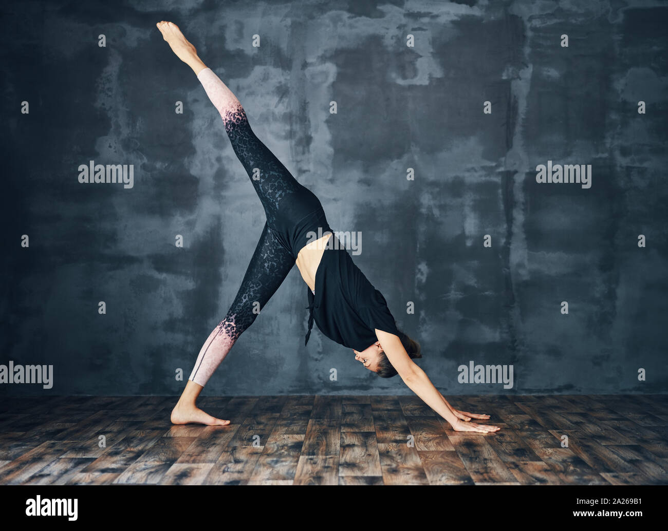 Young sporty woman practicing yoga, doing one legged downward facing ...