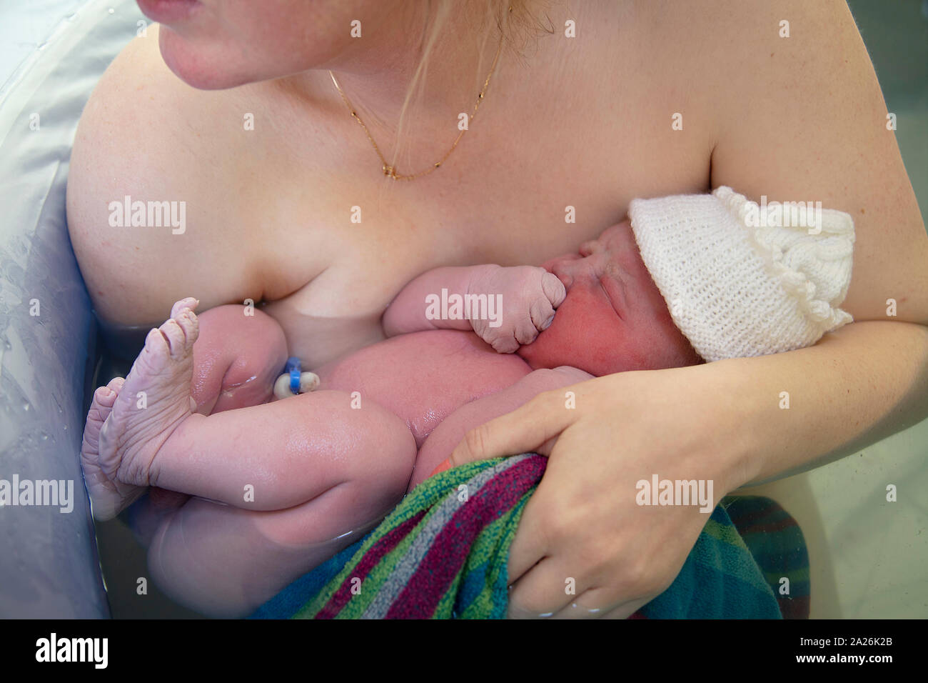 A newborn baby being embraced by their mother after being born Stock Photo