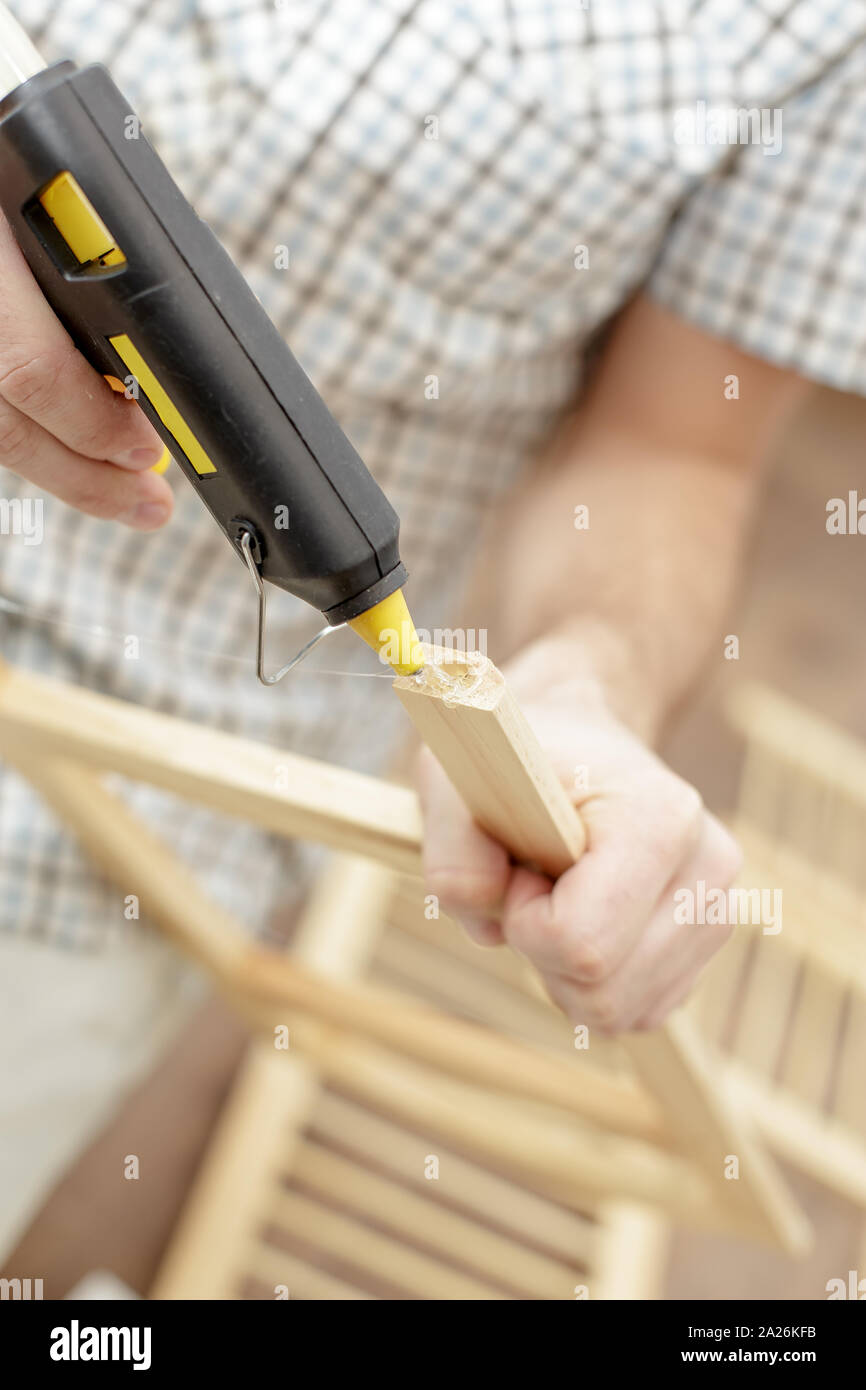 Man putting an electric hot glue gun on wood furniture, close-up Stock  Photo - Alamy