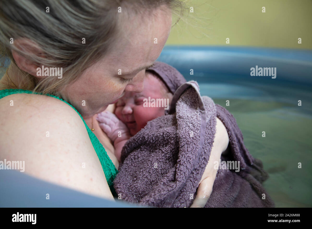 A new mother embracing her newborn baby after a natural pool home birth Stock Photo
