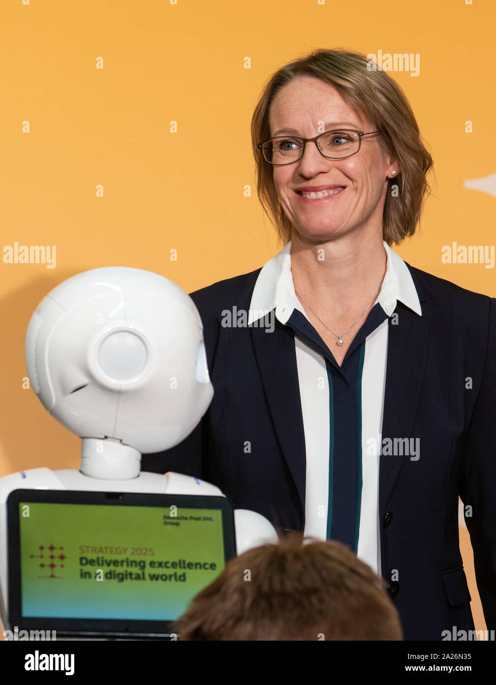 01 October 2019, Hessen, Frankfurt/Main: Melanie Kreis, CFO of Deutsche Post AG, smiles next to a robot before the start of a press conference before presenting Deutsche Post's strategy until 2025. Every five years, the Bonn-based Group updates its approach. Photo: Frank Rumpenhorst/dpa Stock Photo