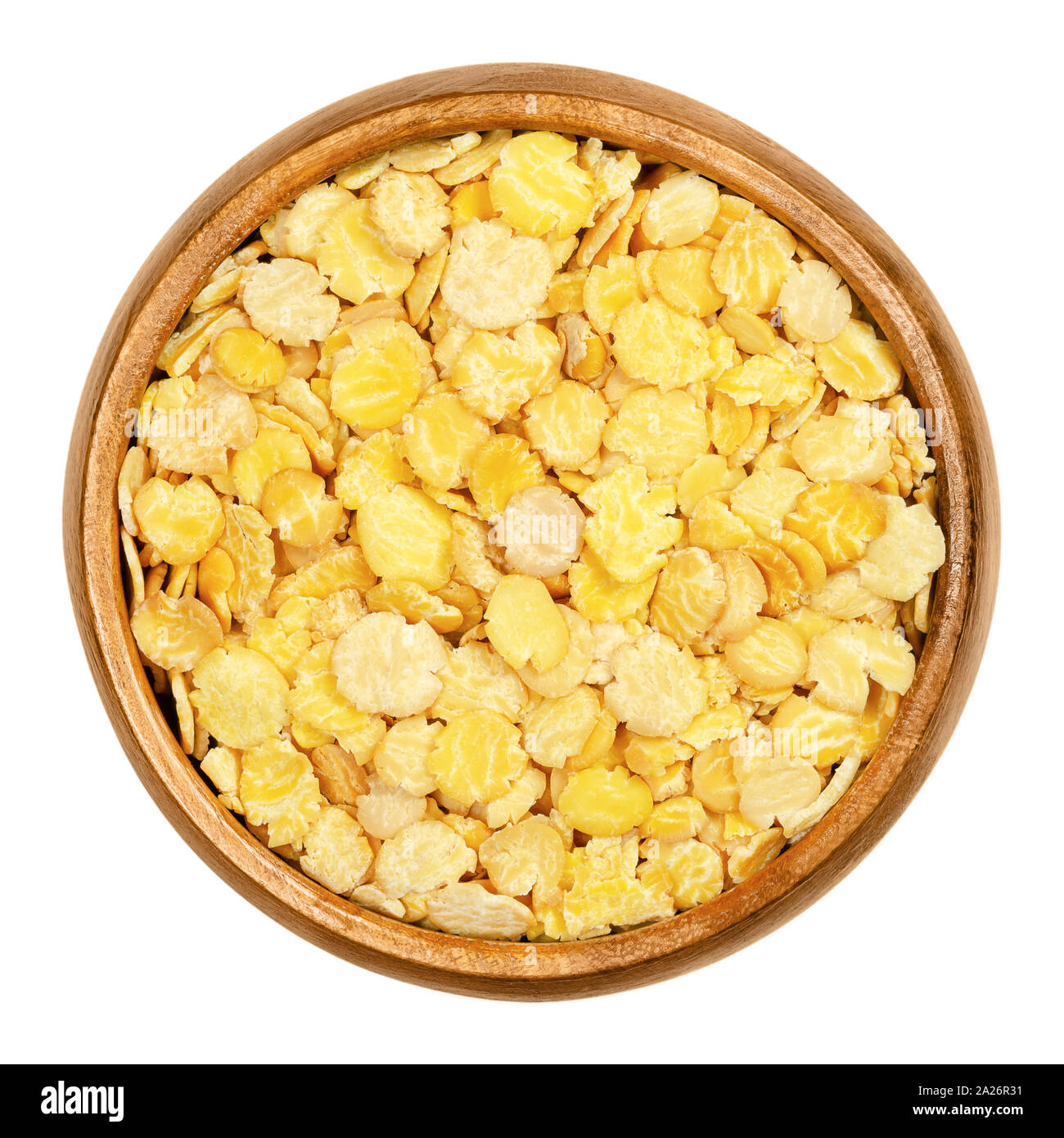 Soya flakes in wooden bowl. Defatted and toasted soybeans, rolled into flakes. Glycine max, also known as soya bean, a legume and oilseed. Stock Photo