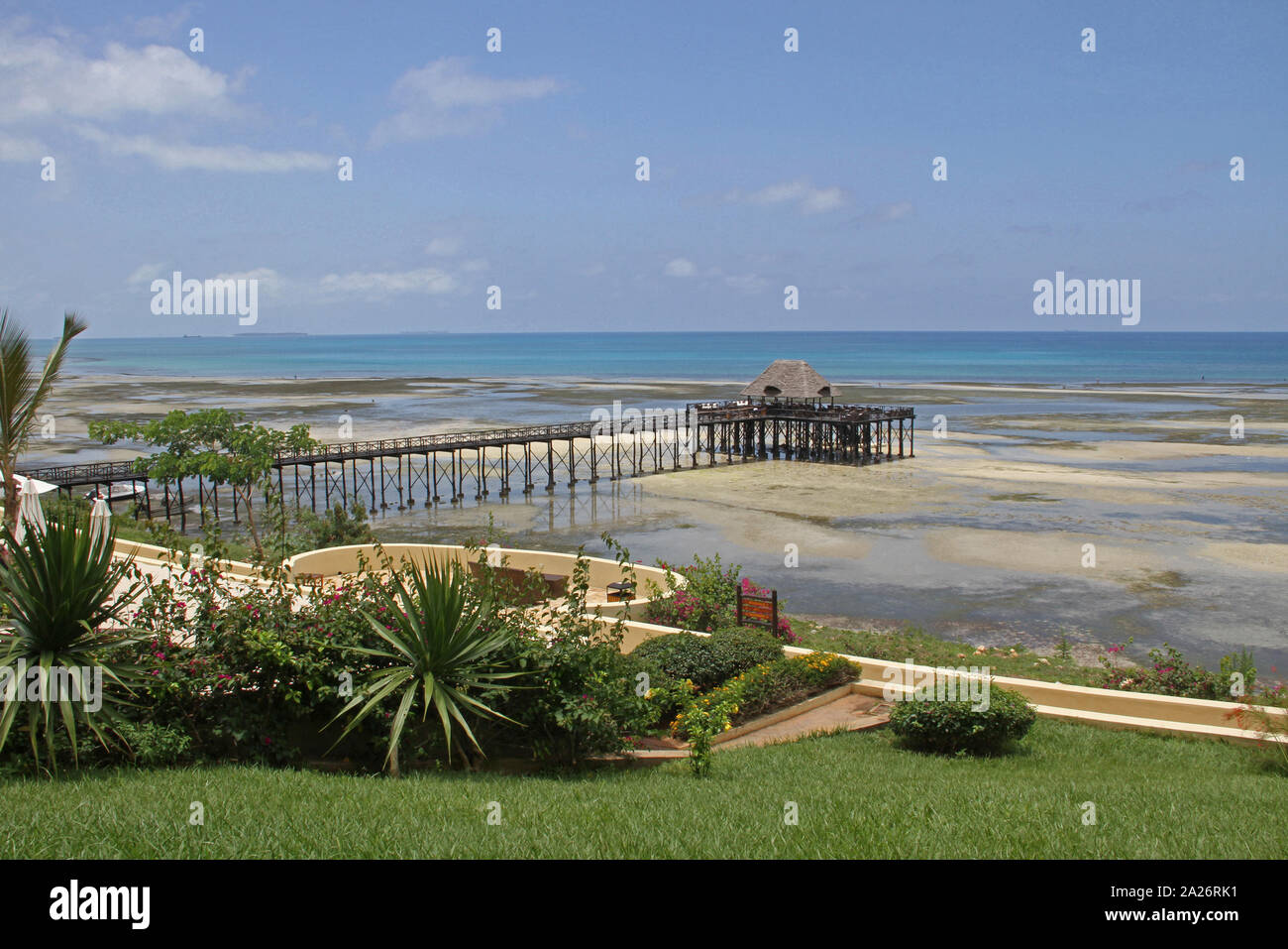 View of pier with a Lapa bar on beach and flowerbed with lawn, off the coast of Zanzibar, Unguja Island, Tanzania. Stock Photo