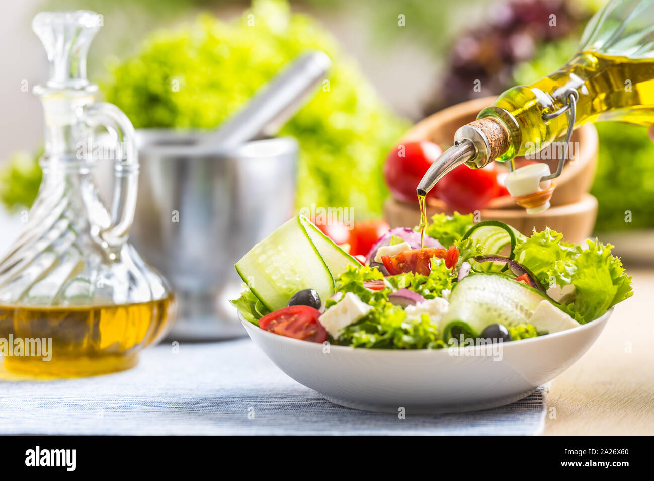 Olive oil pouring in to the fresh vegetable salad. Healthy mediterranean italian or greek cuisine Stock Photo