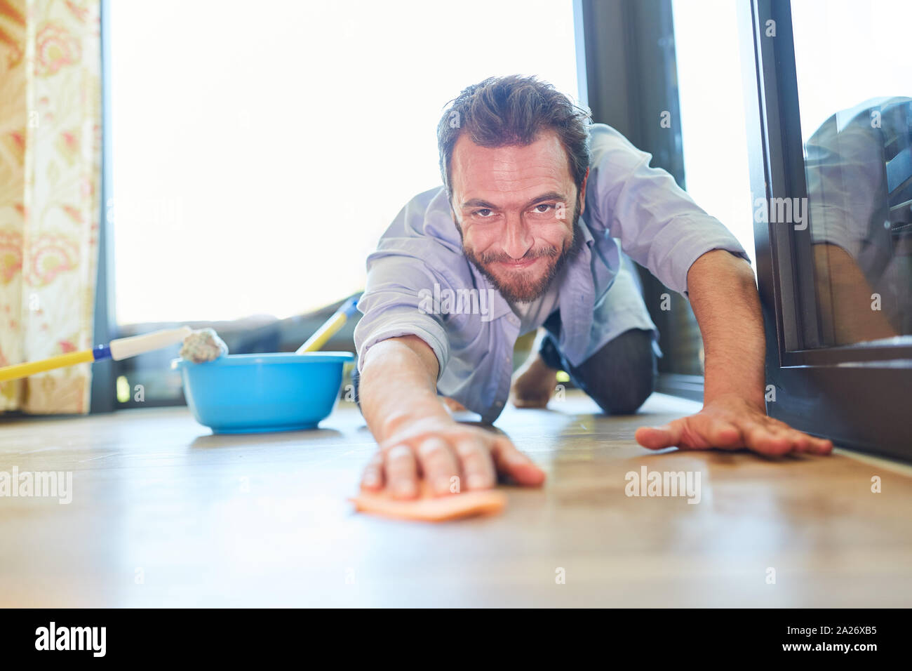 Man as a houseman with wiping cloth at the parquet floor cleaning home Stock Photo Alamy