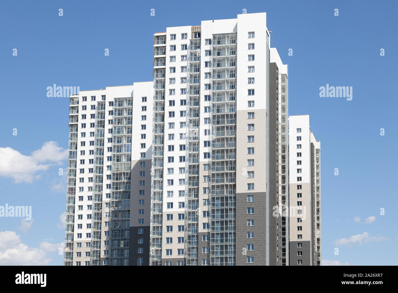 High white-grey multi-family dwelling building against blue sky Stock Photo