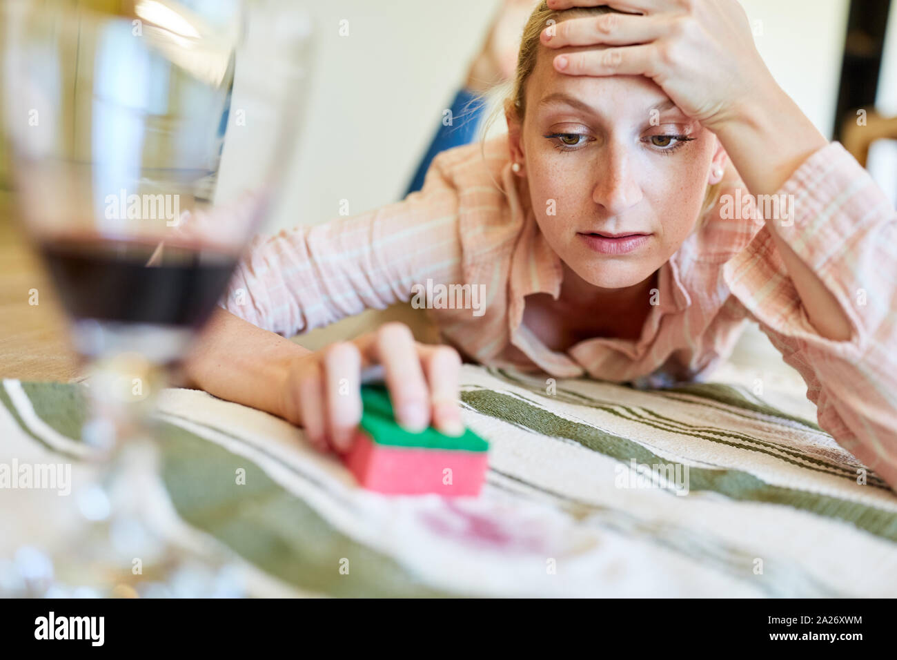 Annoyed housewife removes red wine stains with salt from a carpet Stock Photo