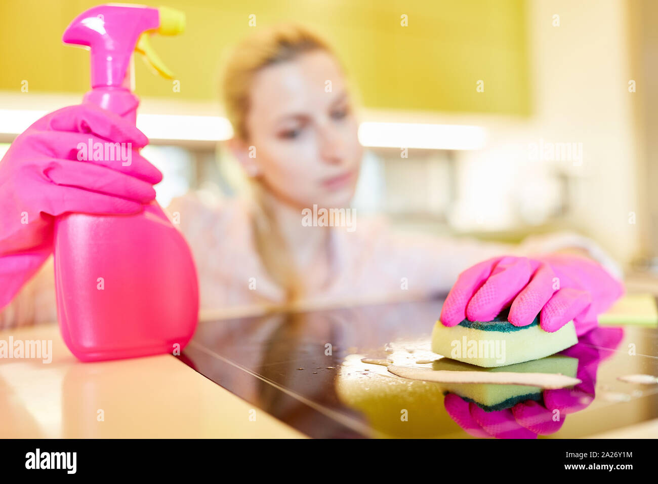Cleaner or cleaning lady with spray bottle and sponge cleans the stove Stock Photo