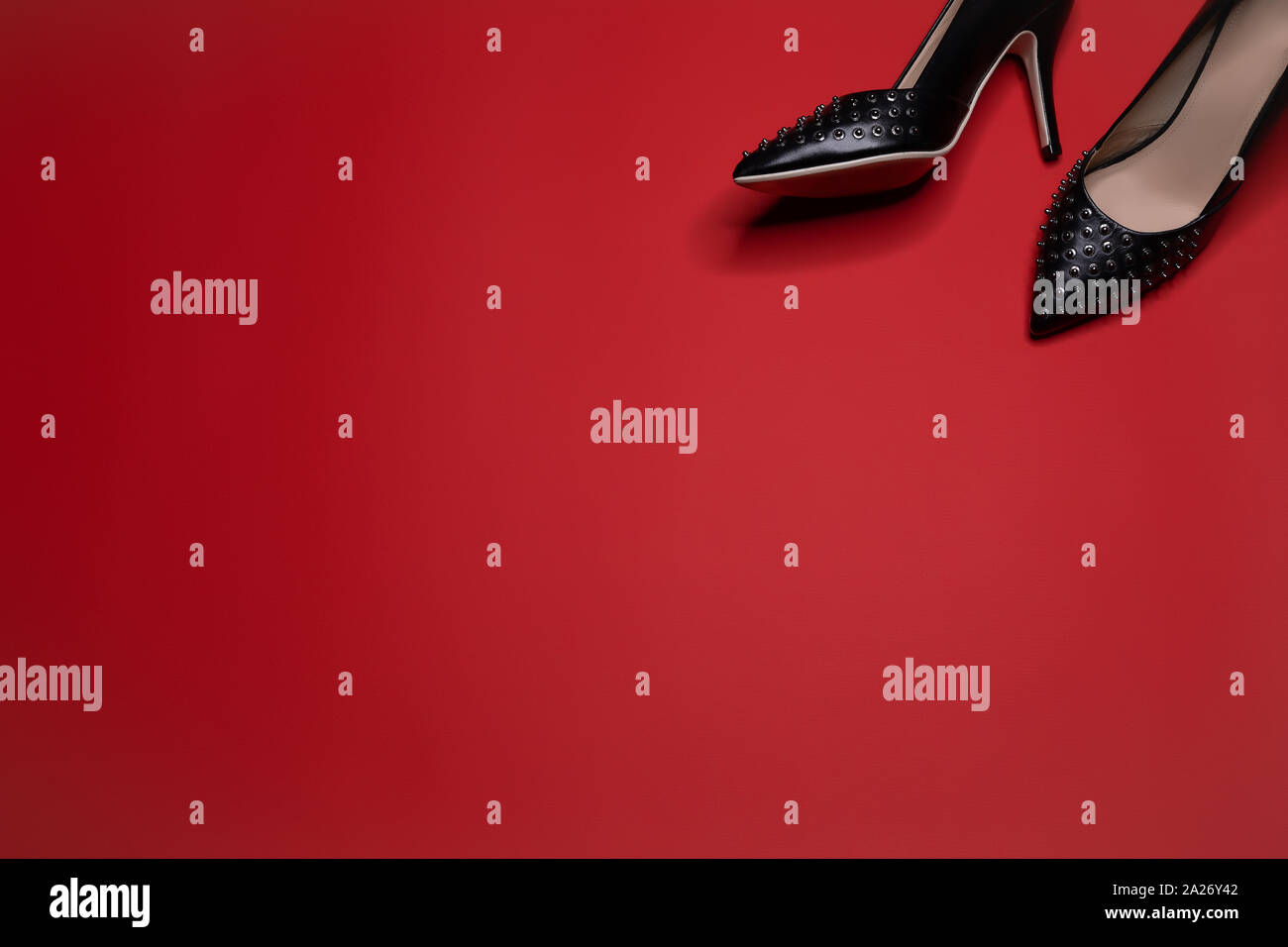 A pair of black leather pumps shoes with spikes and high heels on red  background Stock Photo - Alamy