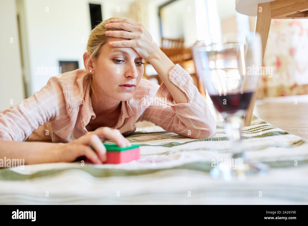 Exhausted housewife in red wine removing stain on carpet in living room Stock Photo