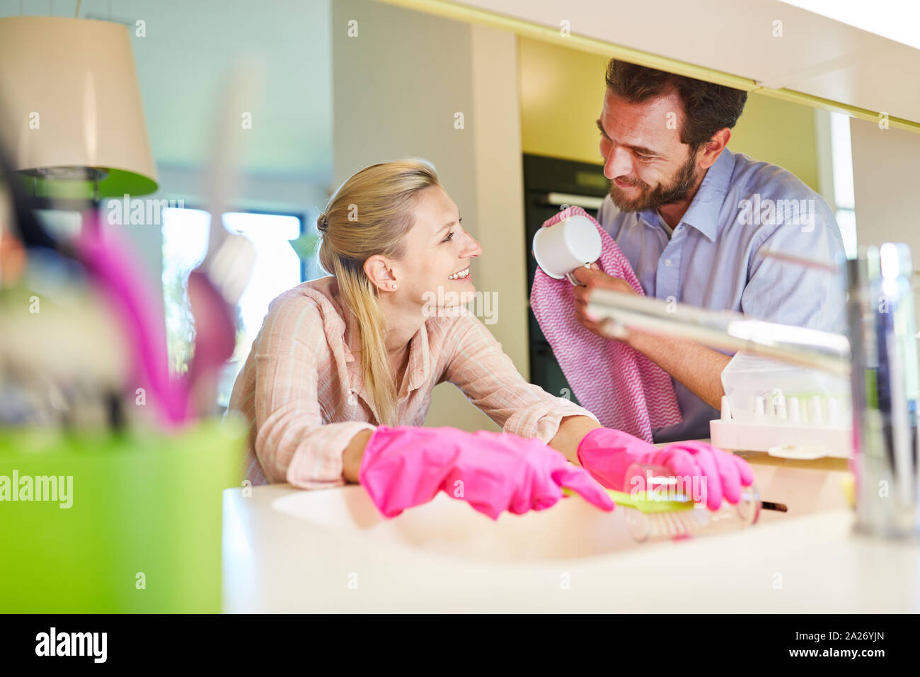 Young couple washing dishes together at the sink in the kitchen Stock Photo