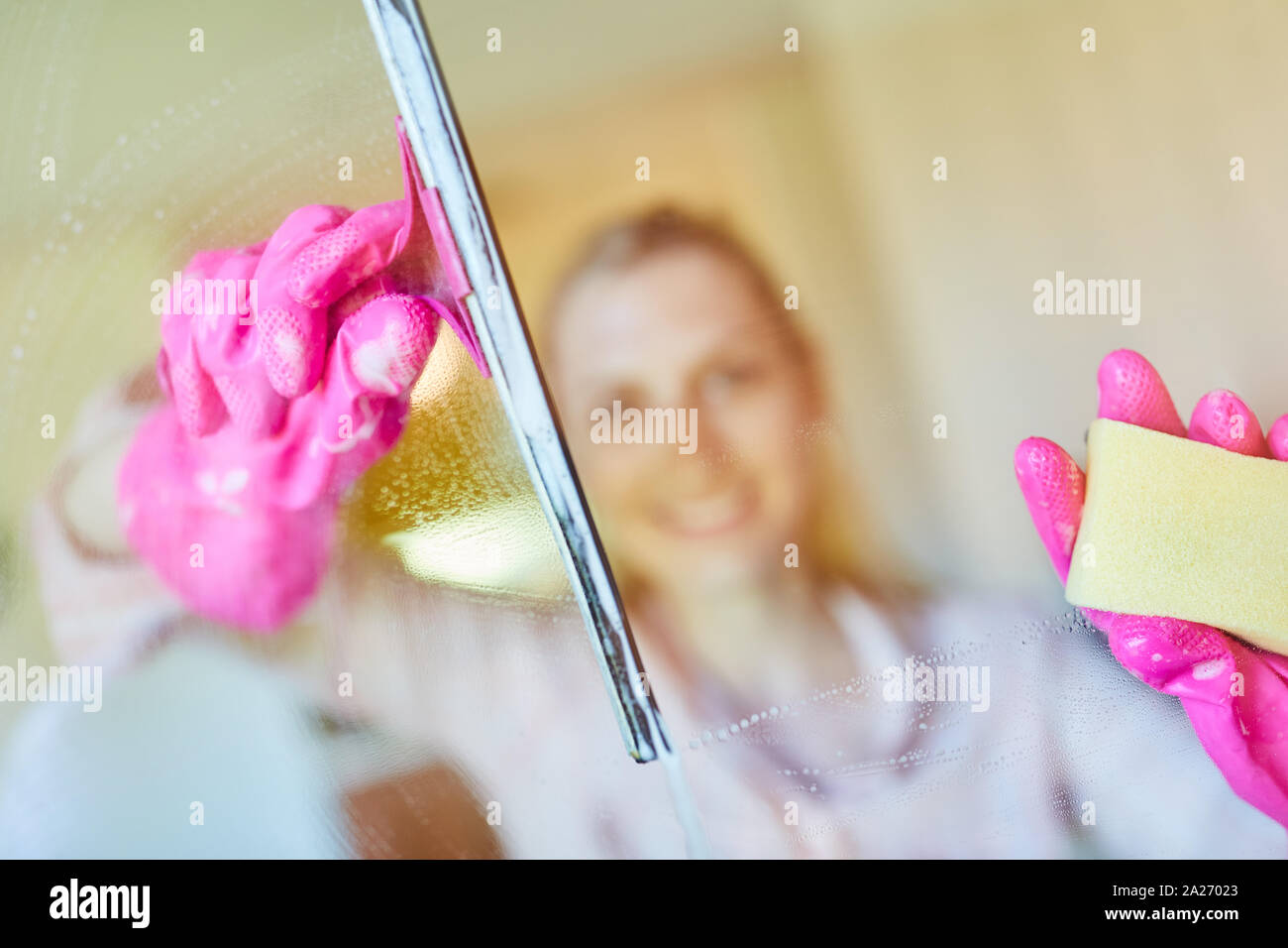 Cleaning lady or domestic help at the window cleaning glass as a