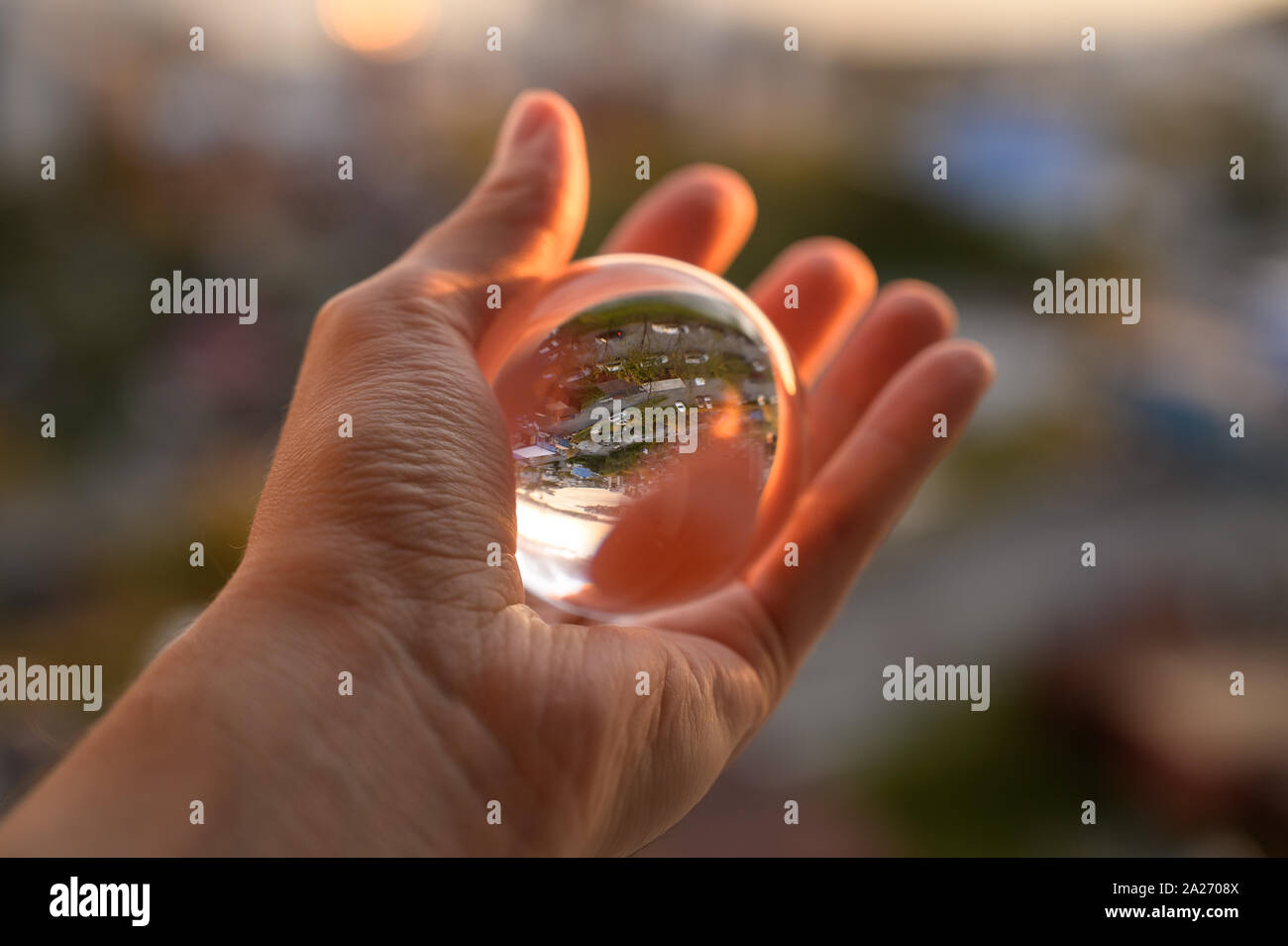 The hand holds glass ball which reflects sunset sky over city Stock ...