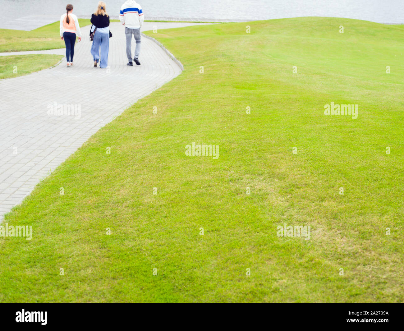 A group of people walking in a park on a footpath, outdoor defocused ...