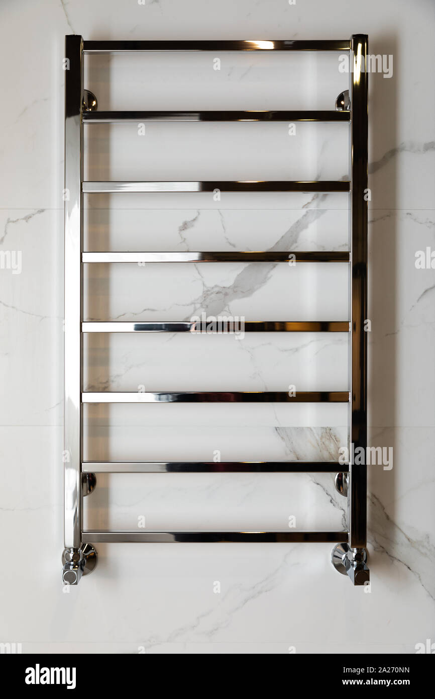 Modern heated towel rail hanging on marble tiled bathroom wall front view  Stock Photo - Alamy