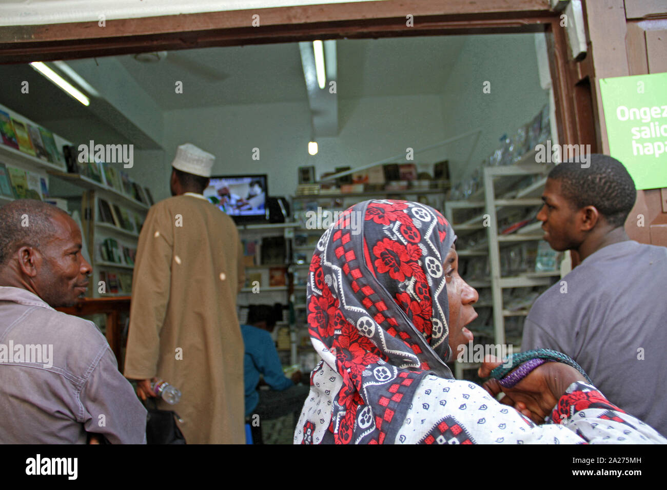 Local Muslim people outside a grocery store, Stone Town, Zanzibar, Unguja Island, Tanzania. Stock Photo