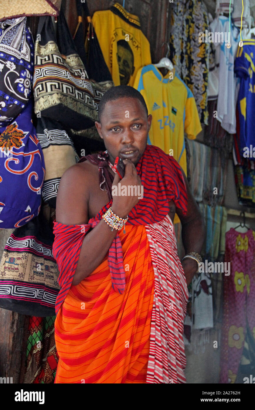 Local Masai vendor in front of clothing shop, Stone Town, Zanzibar, Unguja Island, Tanzania. Stock Photo