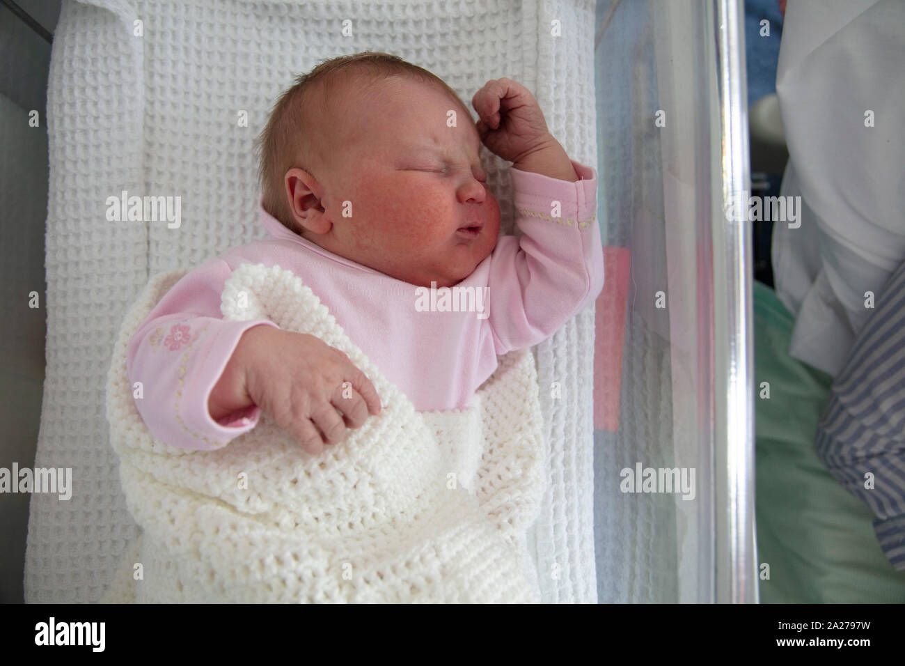 A cute one day old baby asleep in a hospital cot Stock Photo
