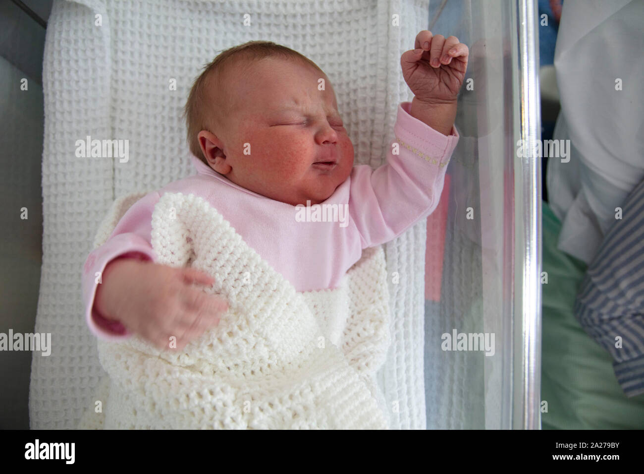 A cute one day old baby asleep in a hospital cot Stock Photo