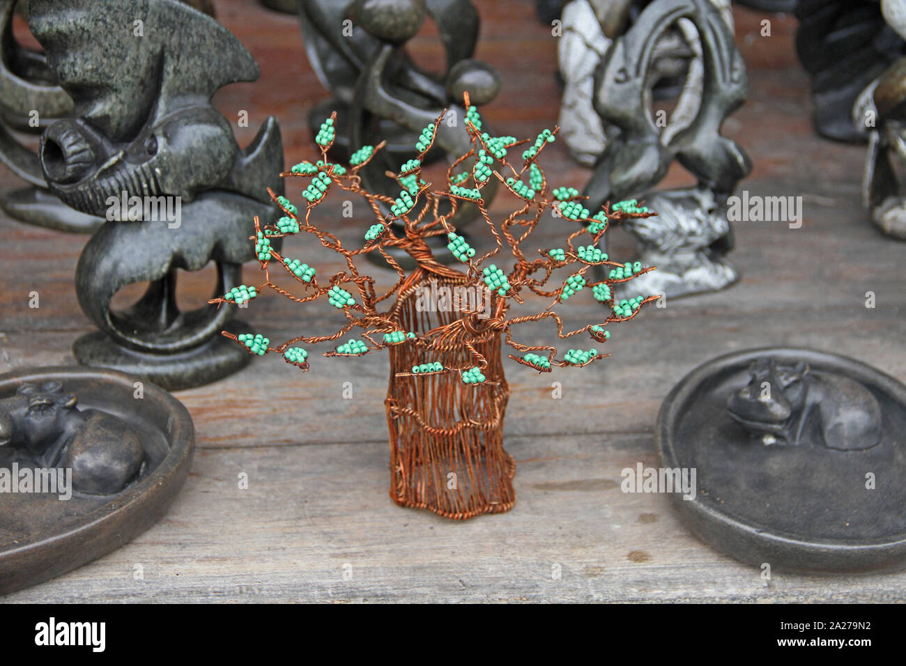 Seafoam green colour beaded copper wire tree surrounded by stone ornaments for sale in market, Zimbabwe. Stock Photo