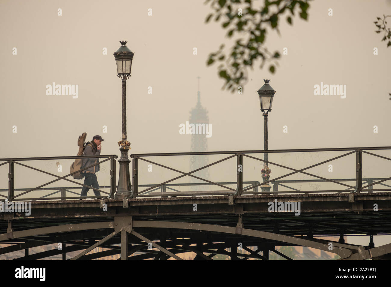 Long shot of man walking across the Pont des Art Paris towards the Louvre Stock Photo