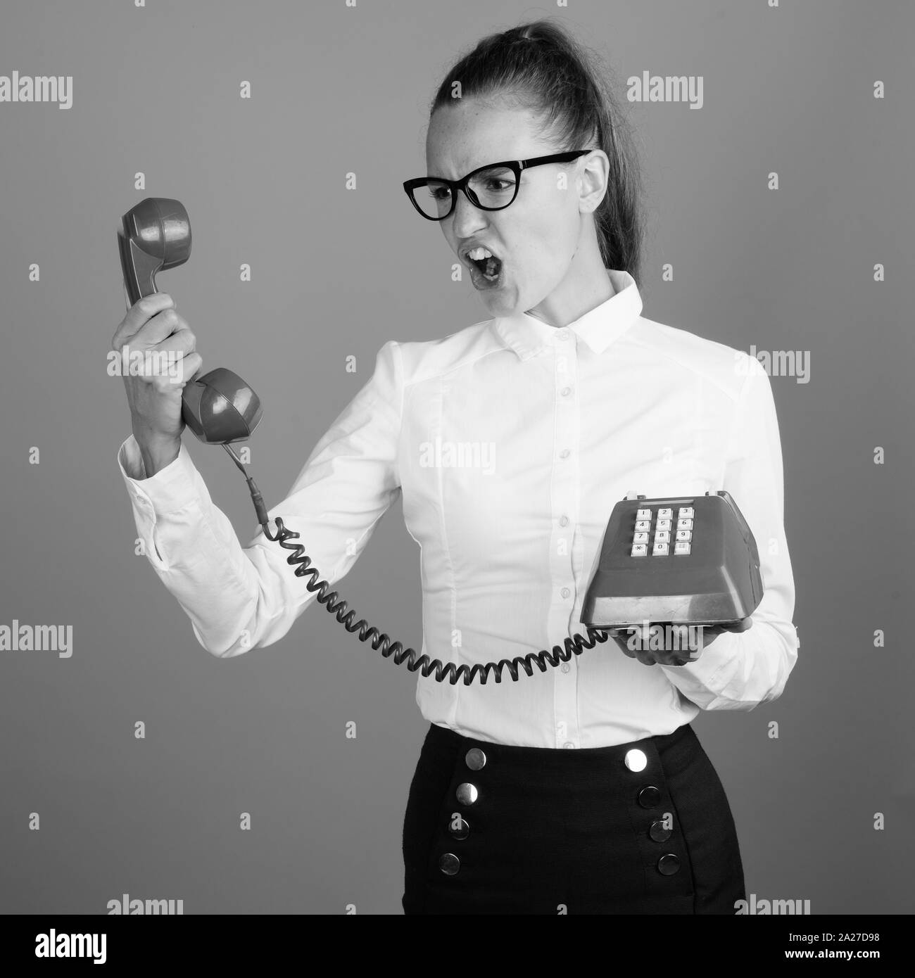 Angry businesswoman screaming to phone shot in black and white Stock Photo