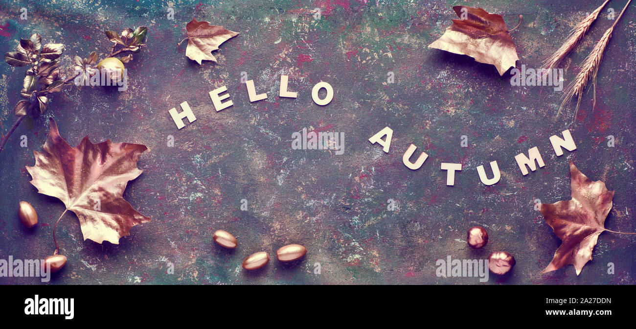 Autumn flat lay with painted golden leaves and text 'Hello Autumn' on dark textured bacgkrdound. Panoramic image, banner composition. Stock Photo