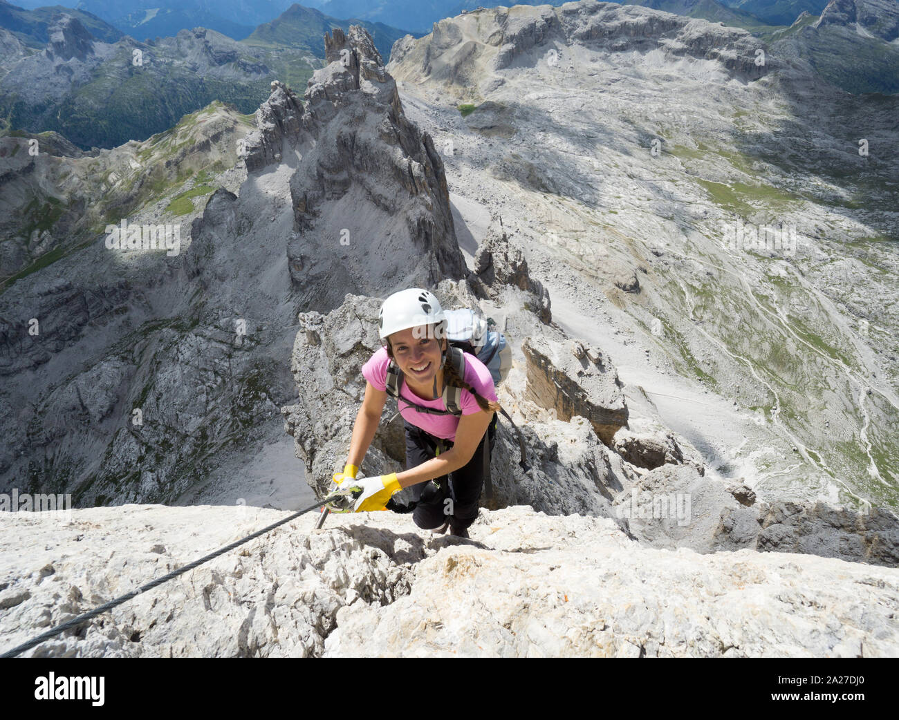 Horizontal view of attractive brunette female climber on a steep and exposed Via Ferrata in the Dolomites Stock Photo