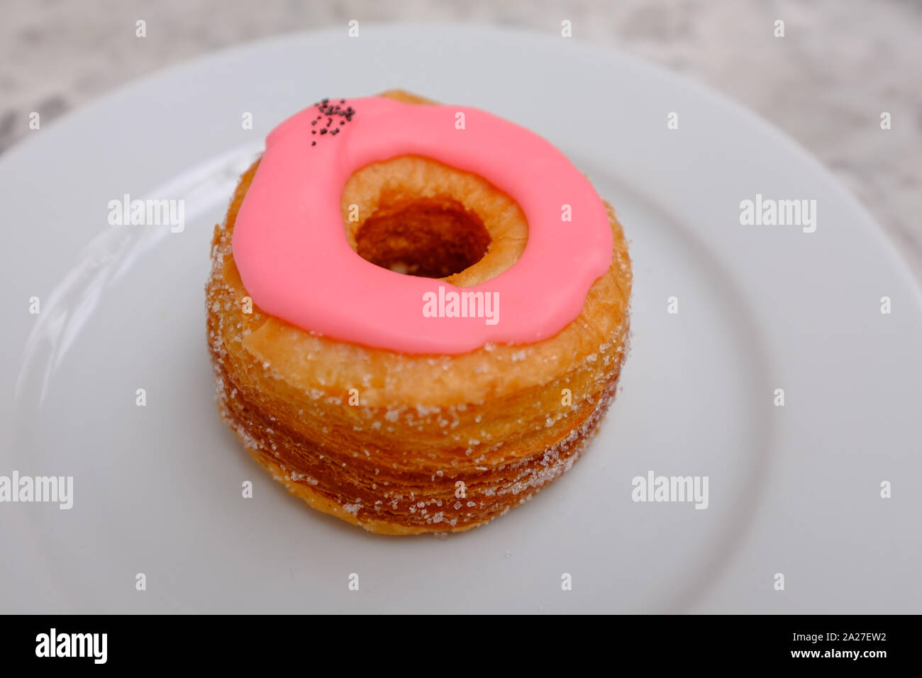 A single pink glazed cronut pastry on a plate at Dominique Ansel Baker, London, England Stock Photo