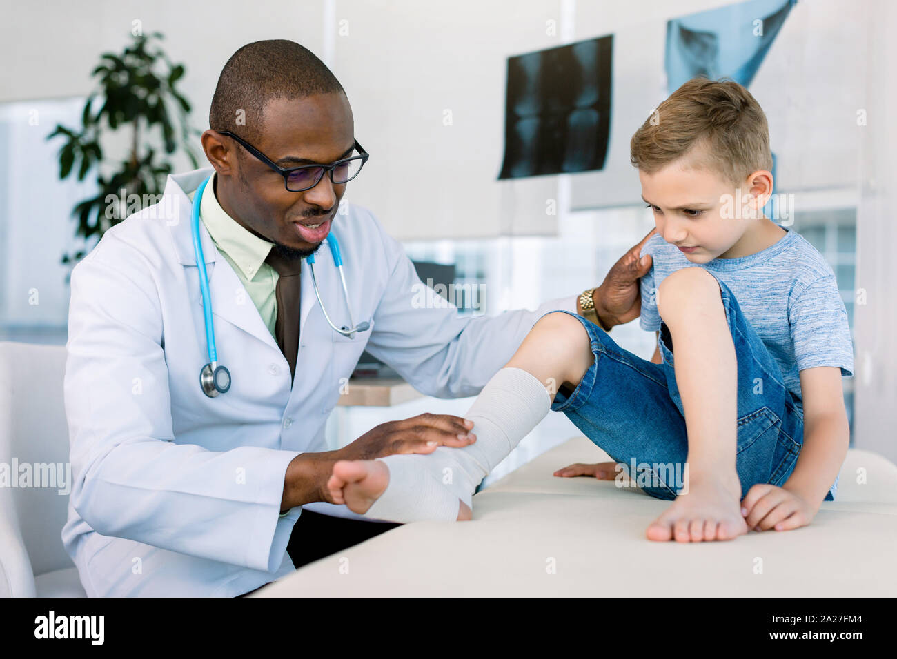 Leg Injured Boy Visiting Young African Doctor Traumatologist In