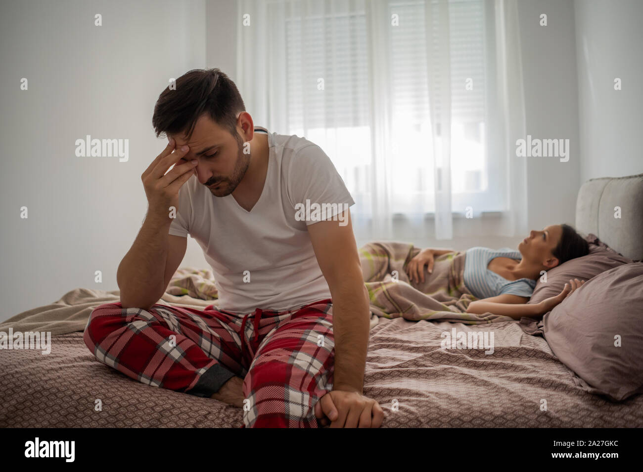 Young man is having insomnia. He wakes up early in the morning. Stock Photo