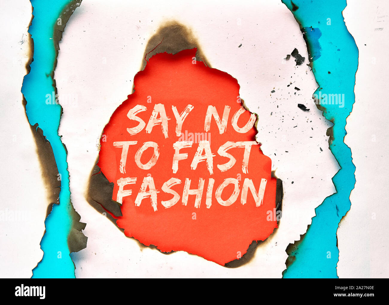 Text 'Say no to fast fashion' in hole burned though white, red and turquoise paper Stock Photo