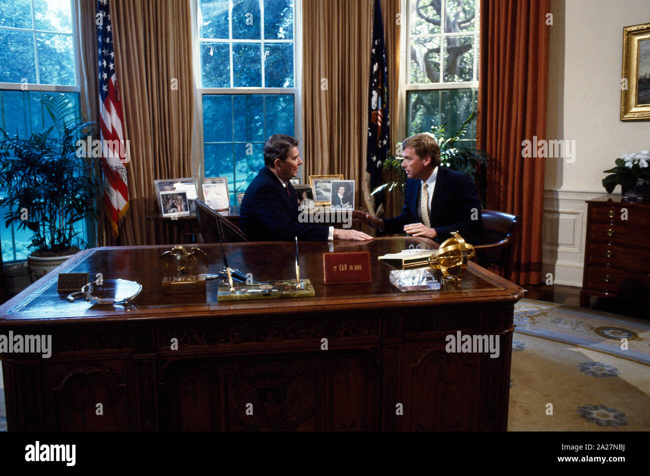 President Ronald Reagan talks to Senator Dan Quayle at his desk in the Oval Office of the White House, Washington, D.C Stock Photo