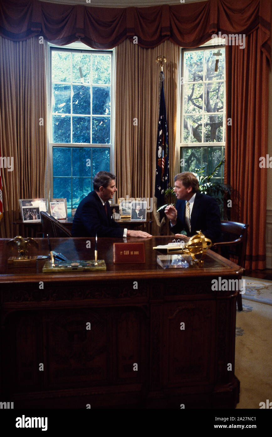 President Ronald Reagan talks to Senator Dan Quayle at his desk in the Oval Office of the White House, Washington, D.C Stock Photo