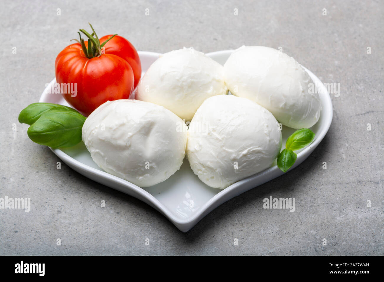 Cheese collection, Italian soft white cheese mozzarella in balls with tomato and basil, love mozzarellaa concept with heart plate Stock Photo